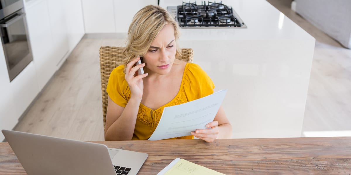 Mujer revisando una carta mientras habla por teléfono