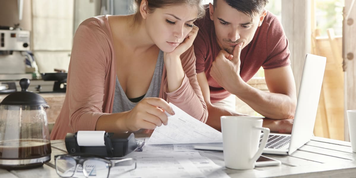 Pareja preocupada revisando documentos en la mesa de la cocina